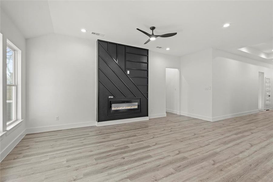 Unfurnished living room with a fireplace, light hardwood / wood-style flooring, ceiling fan, and lofted ceiling