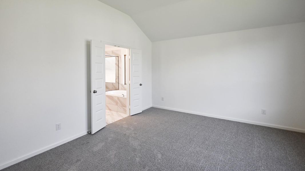 Unfurnished bedroom with lofted ceiling, carpet flooring, and connected bathroom Unfurnished bedroom with lofted ceiling, carpet flooring, and connected bathroom