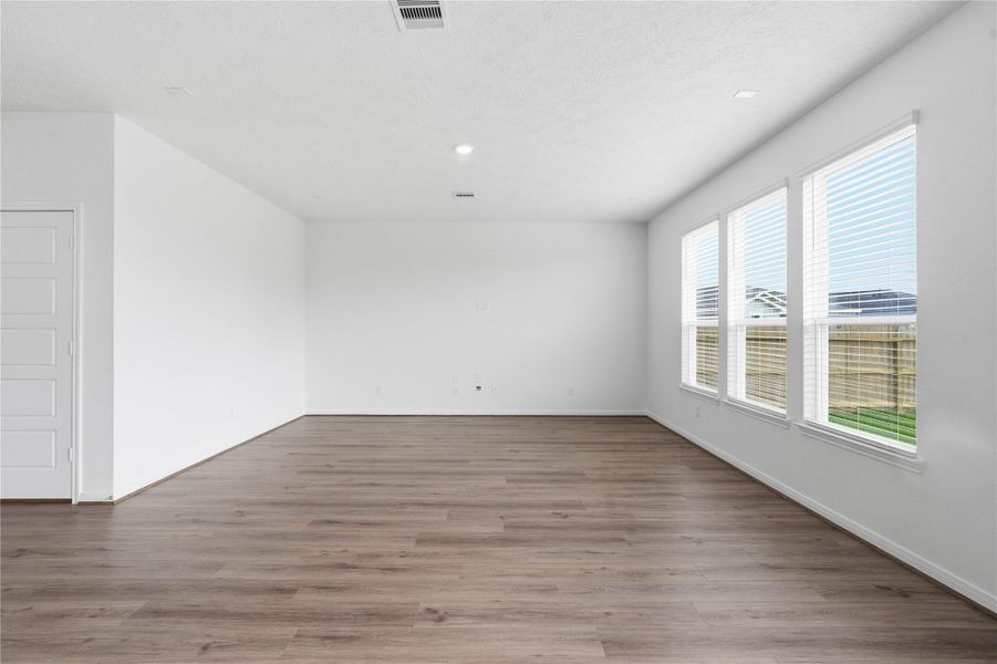 Bring family and friends together in this beautiful family room! It features high ceilings, recessed lighting, custom paint, stunning vinyl plank flooring, and large windows!