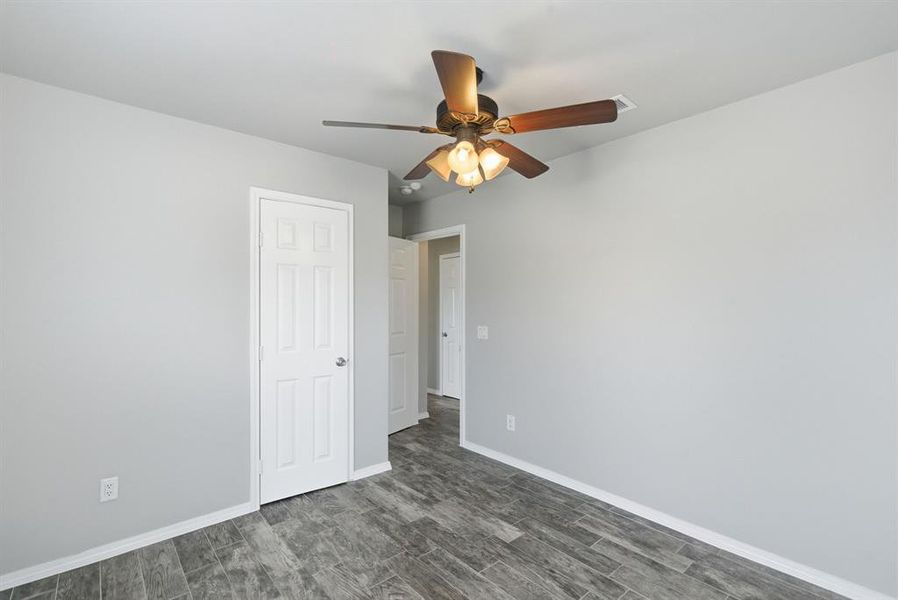 Unfurnished bedroom with dark wood-style flooring and a ceiling fan Unfurnished bedroom with dark wood-style flooring and a ceiling fan