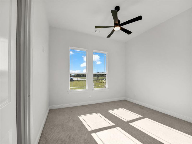 Empty room with ceiling fan and light colored carpet