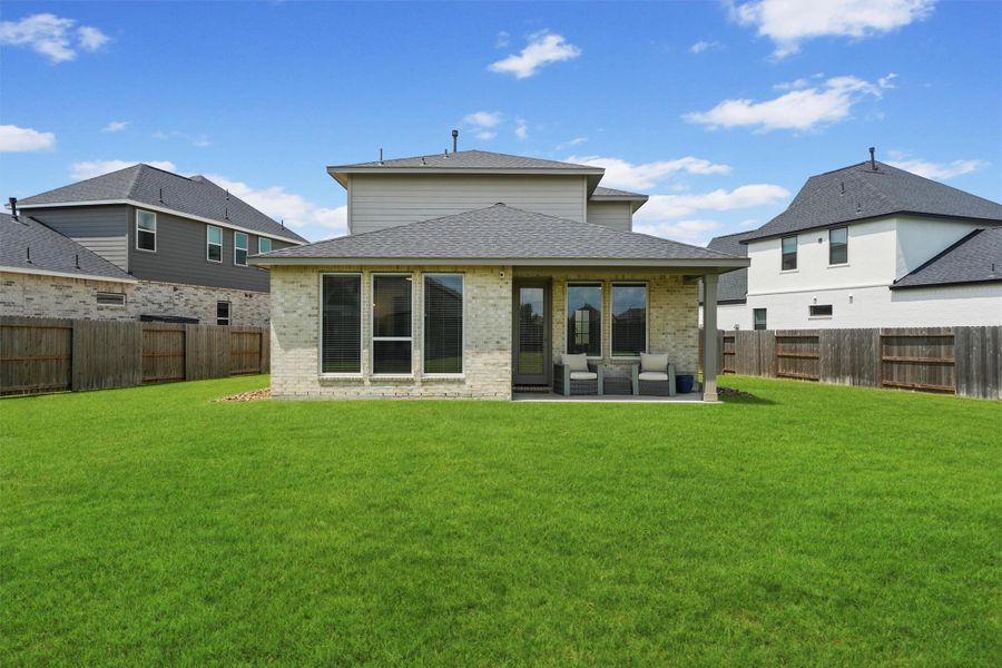 The back of the home highlights the generous lot and expansive backyard, which is fully fenced for privacy. This property offers plenty of side yard space on both sides of the house, providing a truly versatile outdoor living experience.