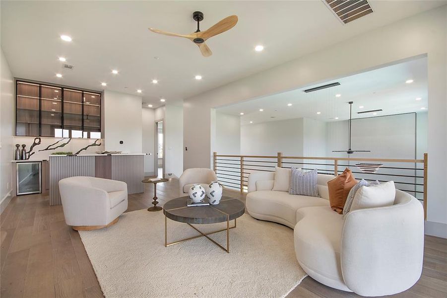 Living room featuring ceiling fan, bar, wood finished floors, wine cooler, and recessed lighting