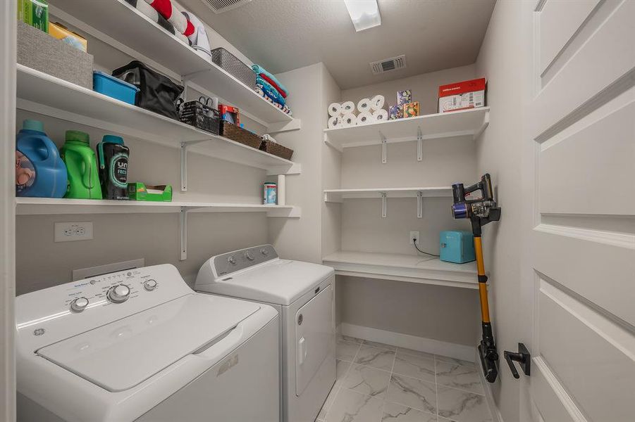 Laundry room featuring light marble finish floors and washer and dryer