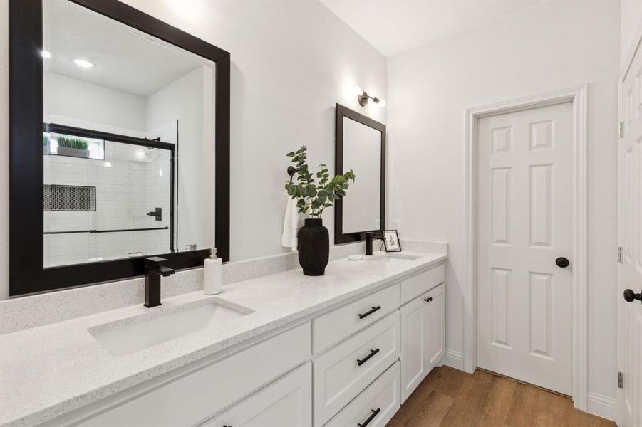 Bathroom featuring hardwood / wood-style floors, vanity, and an enclosed shower