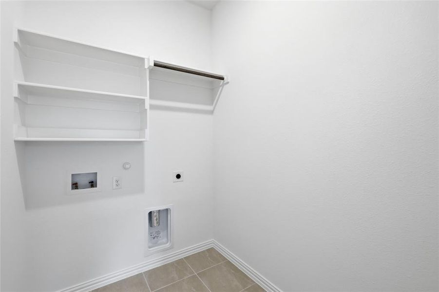 Dedicated laundry area featuring built-in shelving, a garment rod, appliance hookups, and tiled flooring