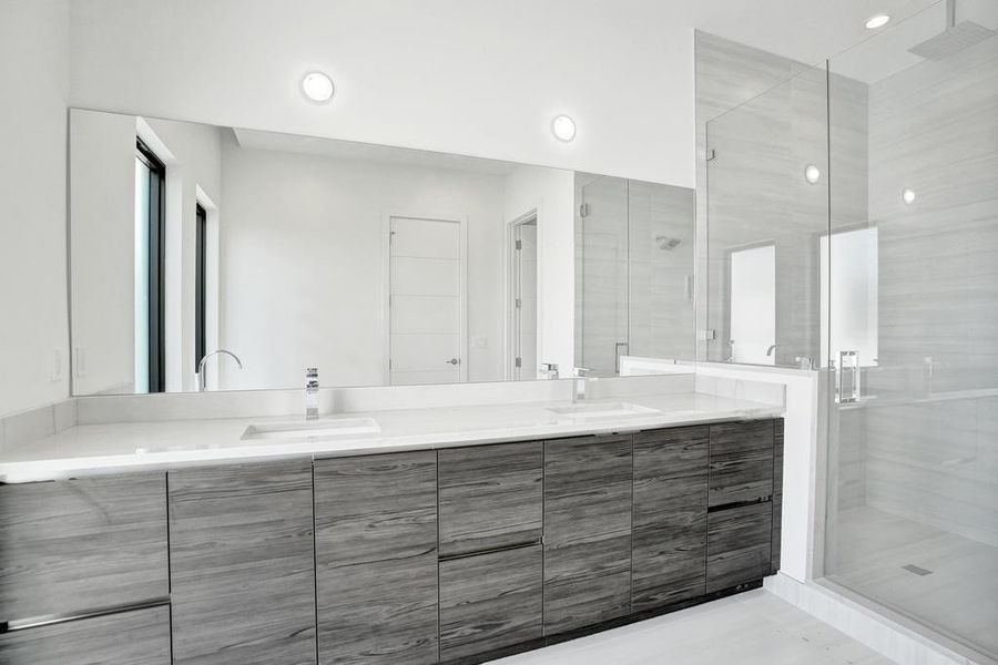 Primary Bath Detail — Dual vanities with custom cabinetry, designer fixtures, and a beautifully designed shower enhanced by an optional overhead rain feature for a spa-like experience. — Pre-wired for buyer-selected vanity lighting.