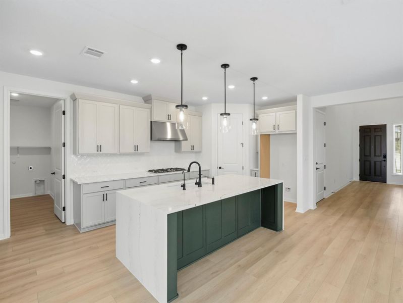 A well-lit kitchen with a striking two-tone island and bright hardwood flooring invites culinary exploration. A well-lit kitchen with a striking two-tone island and bright hardwood flooring invites culinary exploration.