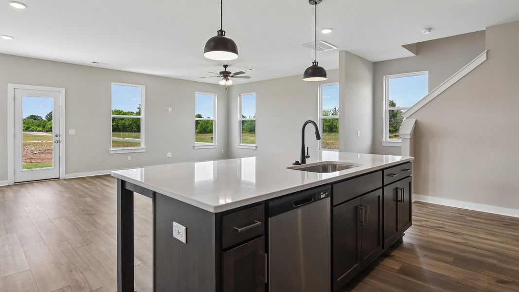 Kitchen with dark cabinetry, quartz countertops, pendant lighting, and tile backsplash