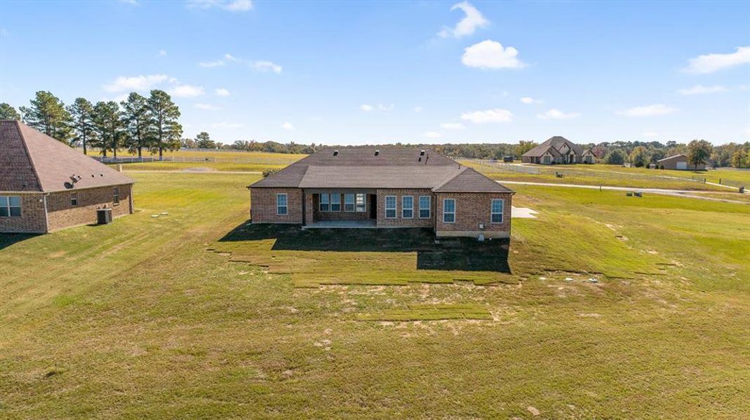 Back of house featuring a yard, a patio area, and brick siding Back of house featuring a yard, a patio area, and brick siding