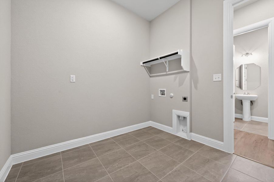 Washroom with hookup for a gas dryer, light tile patterned floors, hookup for an electric dryer, and hookup for a washing machine