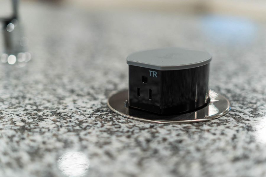 The elegant granite island features convenient, modern amenities, including a sleek, pop-up power receptacle, ensuring your countertop remains clutter-free and stylish while you cook or entertain.