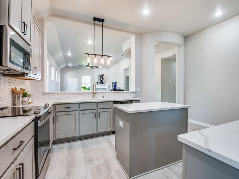 Kitchen featuring light wood-style flooring, gray cabinets, a sink, stainless steel appliances, and backsplash Kitchen featuring light wood-style flooring, gray cabinets, a sink, stainless steel appliances, and backsplash