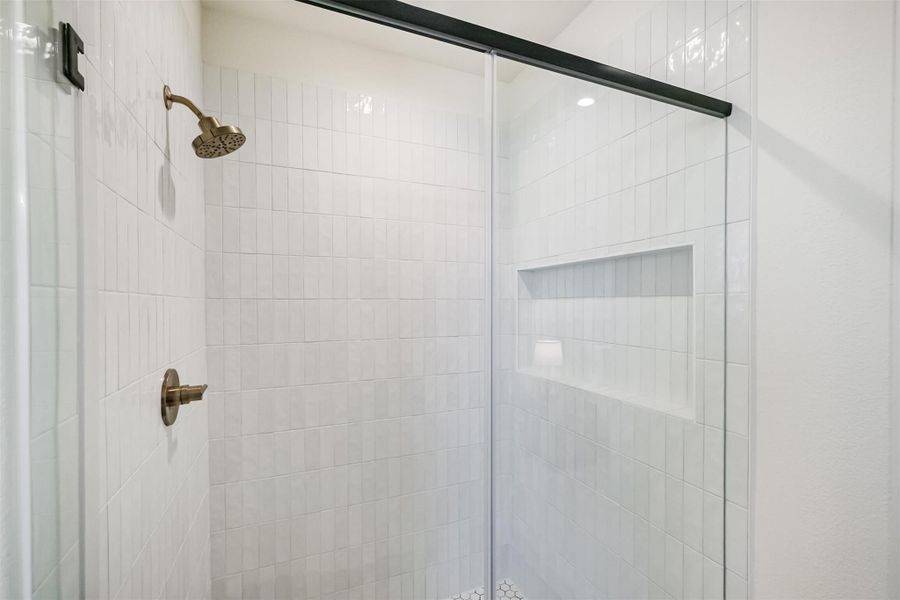 Modern walk-in shower with white subway tile, glass door, and built-in niche.