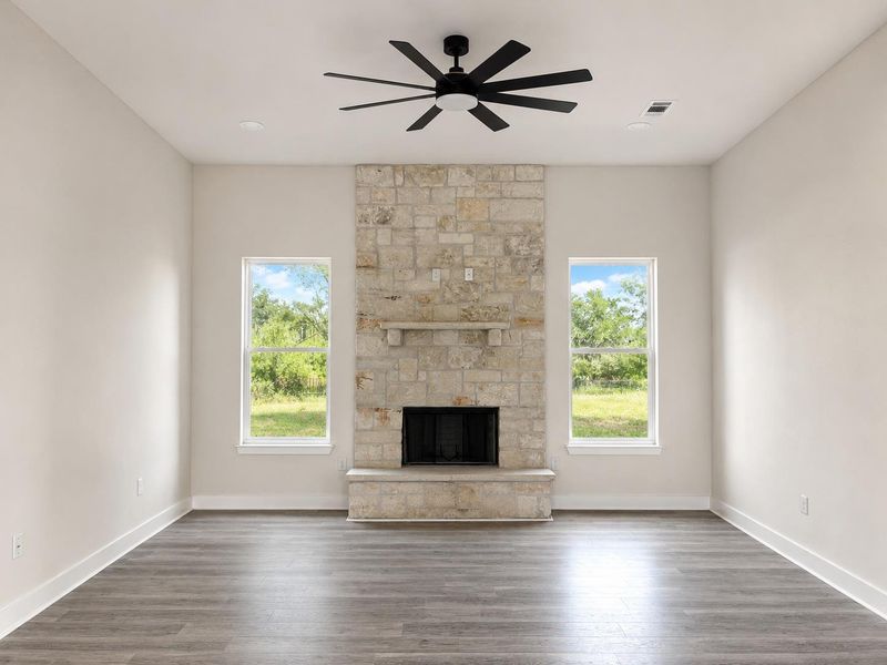 A striking stone fireplace anchors this living space, offering warmth and a scenic backyard view.