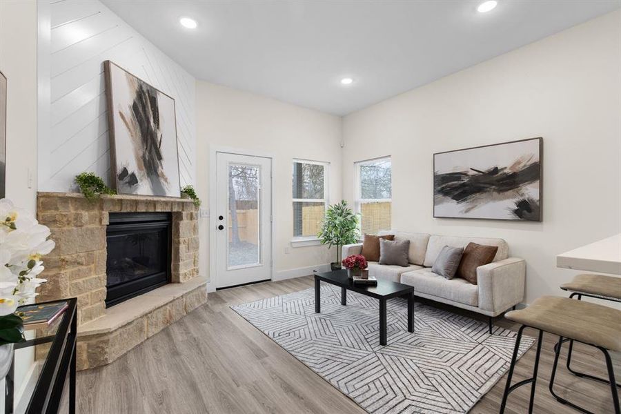 Living room with light hardwood / wood-style floors and a stone fireplace