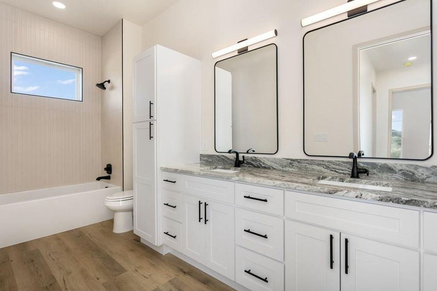 Full bathroom featuring double vanity, light wood-style floors, bathing tub / shower combination, and recessed lighting Full bathroom featuring double vanity, light wood-style floors, bathing tub / shower combination, and recessed lighting