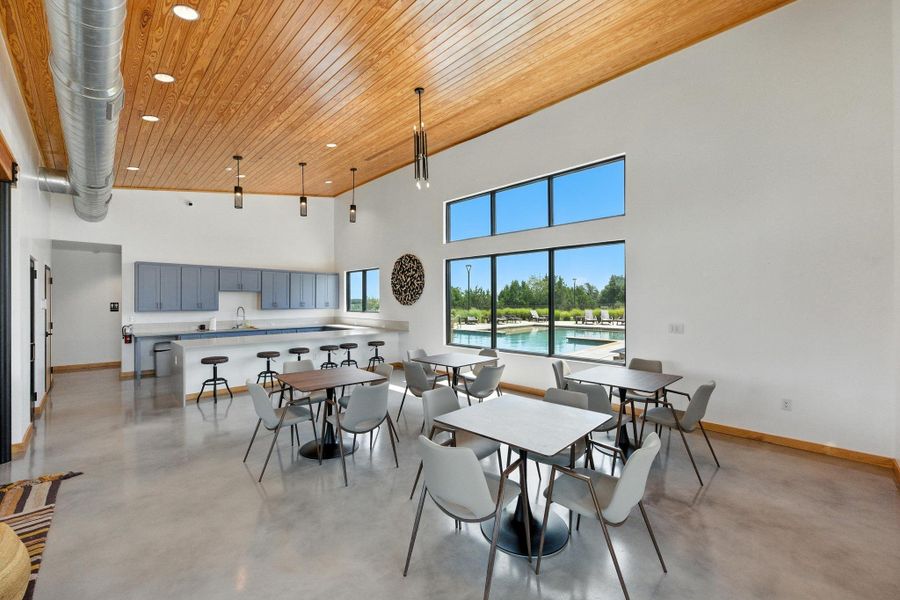Community area for residents featuring concrete floors, a high ceiling, wooden ceiling, and recessed lighting