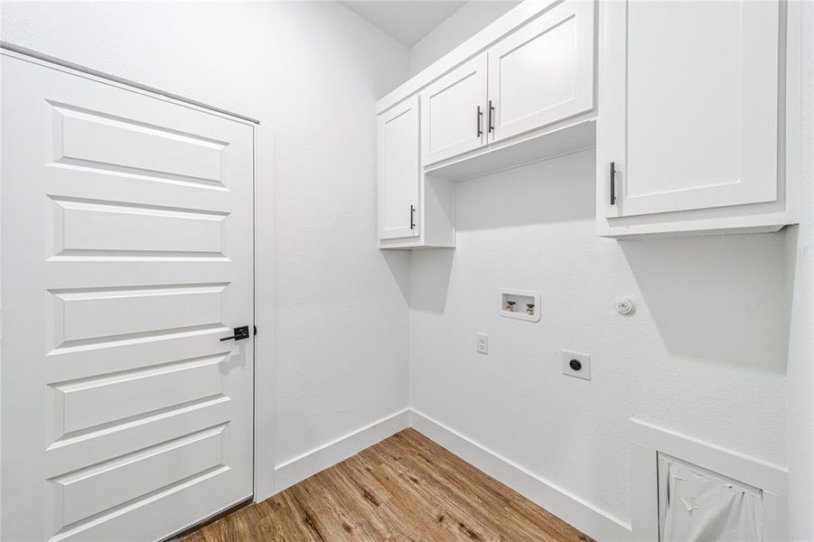 Washroom with light wood-type flooring, gas dryer hookup, hookup for an electric dryer, hookup for a washing machine, and cabinet space