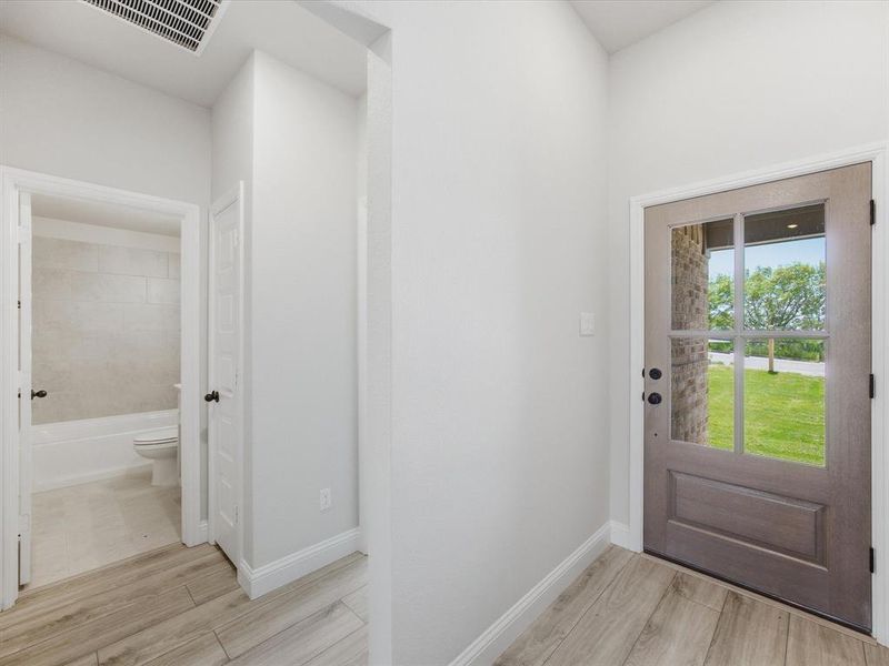 Entryway featuring wood-finish flooring, a six-panel glass-inset door, and a brick exterior accent Entryway featuring wood-finish flooring, a six-panel glass-inset door, and a brick exterior accent