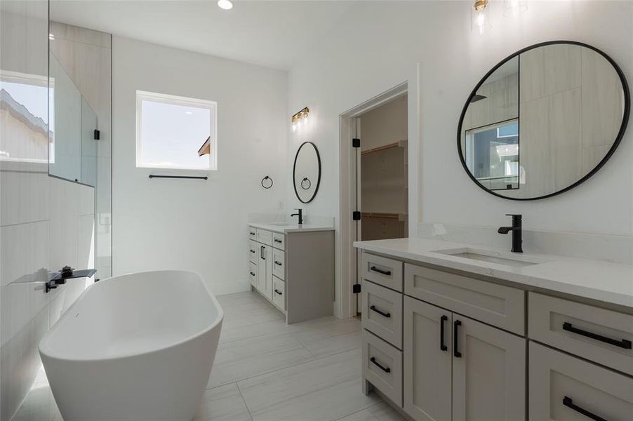 Bathroom featuring two vanities and a soaking tub