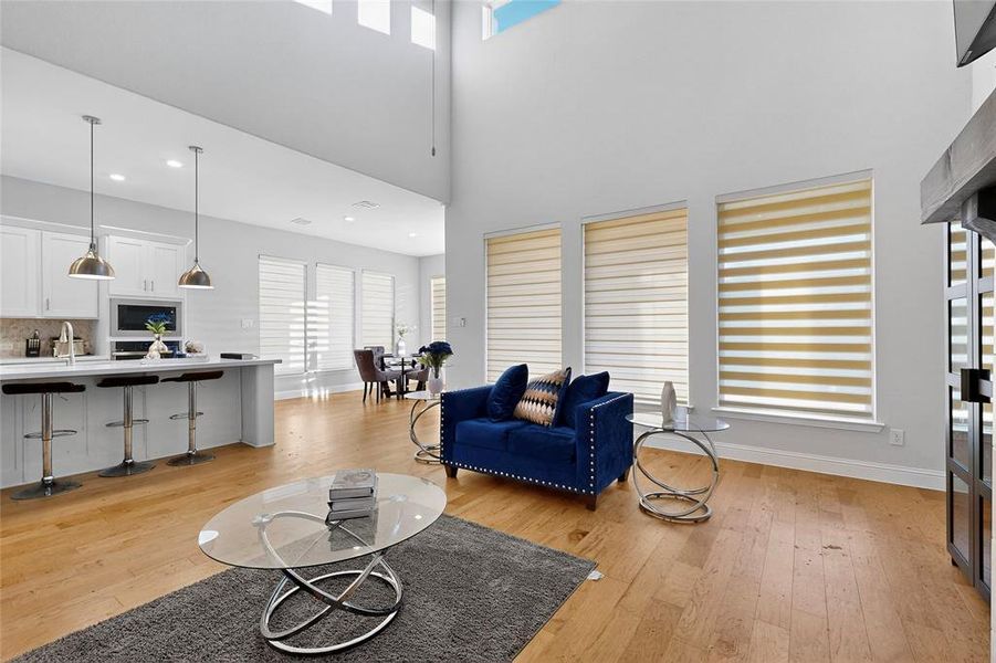Living room featuring light wood-type flooring, a high ceiling, and recessed lighting