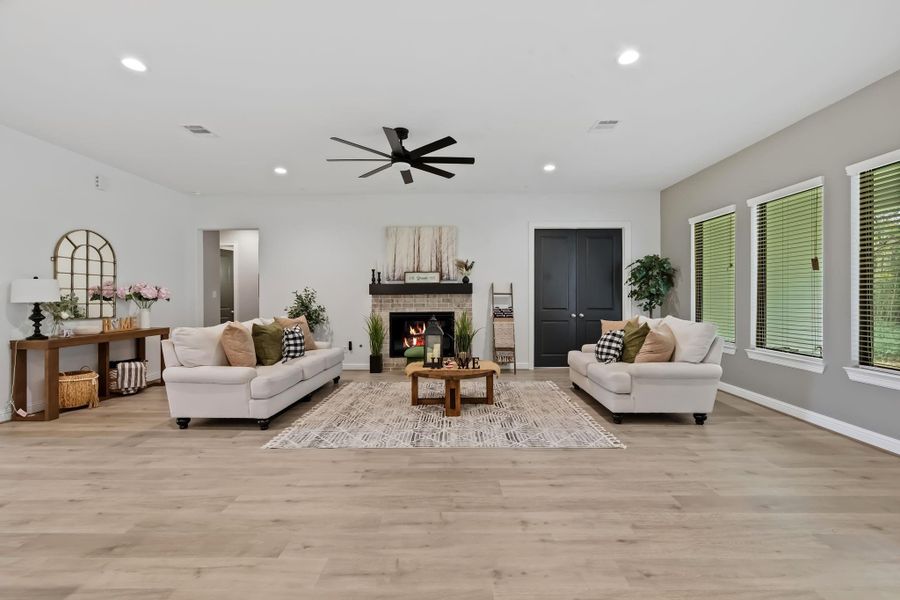 The family area has recessed lighting, LVP whitewashed oak flooring, ceiling fan, and a gaslog fireplace.