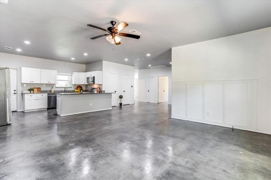Open-concept living space featuring polished concrete flooring, recessed lighting, and a ceiling fan