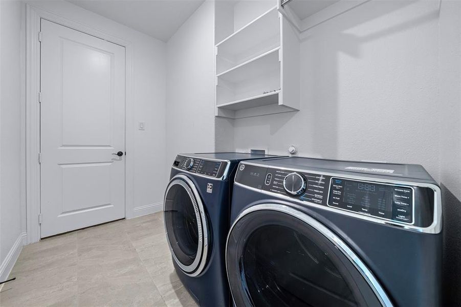 Laundry room with washer and clothes dryer and baseboards