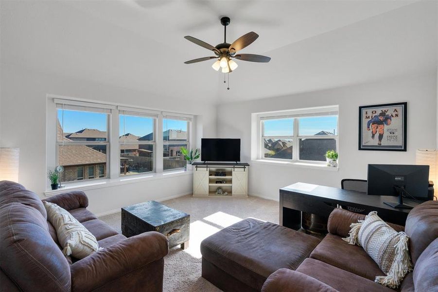 Living room featuring plenty of natural light, ceiling fan, lofted ceiling, and light carpet