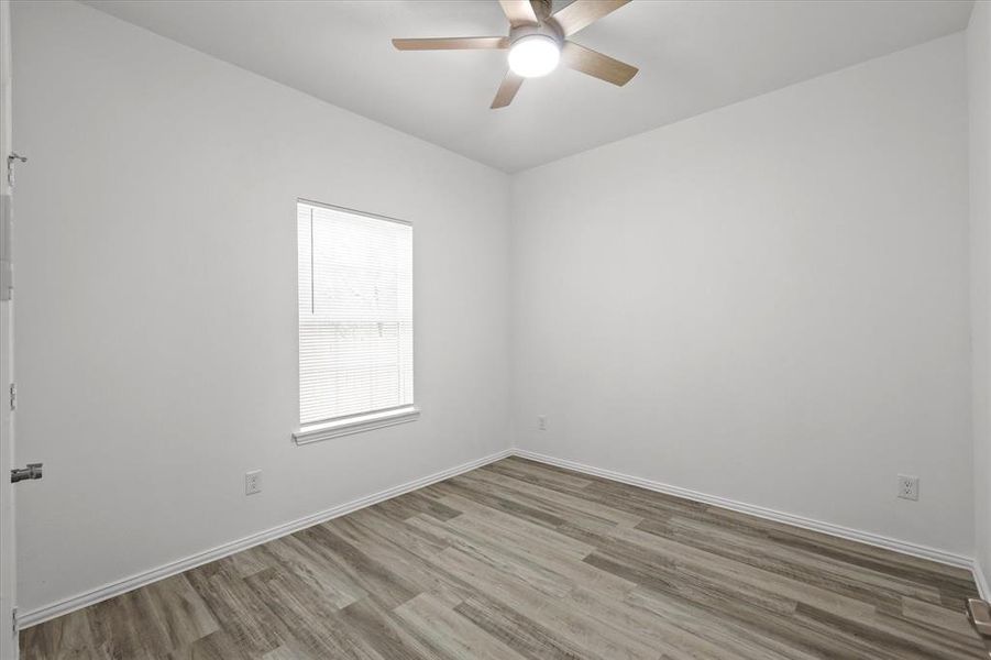 Empty room with wood finished floors, a ceiling fan, and baseboards