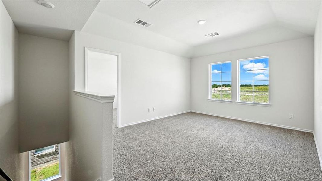 Spacious upper-level room featuring two prominent windows, plush gray carpeting, and recessed lighting