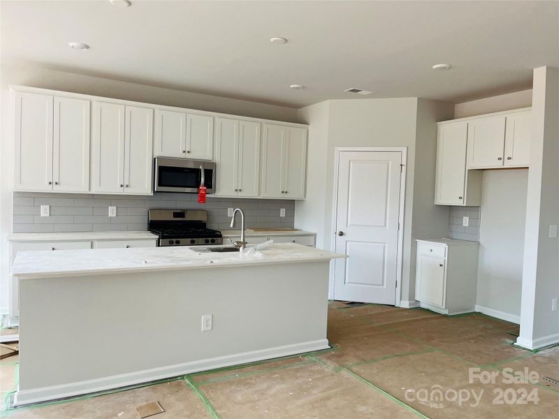 Kitchen with a large island, huge pantry and quartz countertops.