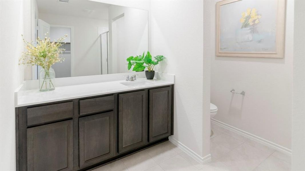 Bathroom vanity featuring a light countertop, dark wood-finish cabinetry, and a wide mirror Bathroom vanity featuring a light countertop, dark wood-finish cabinetry, and a wide mirror