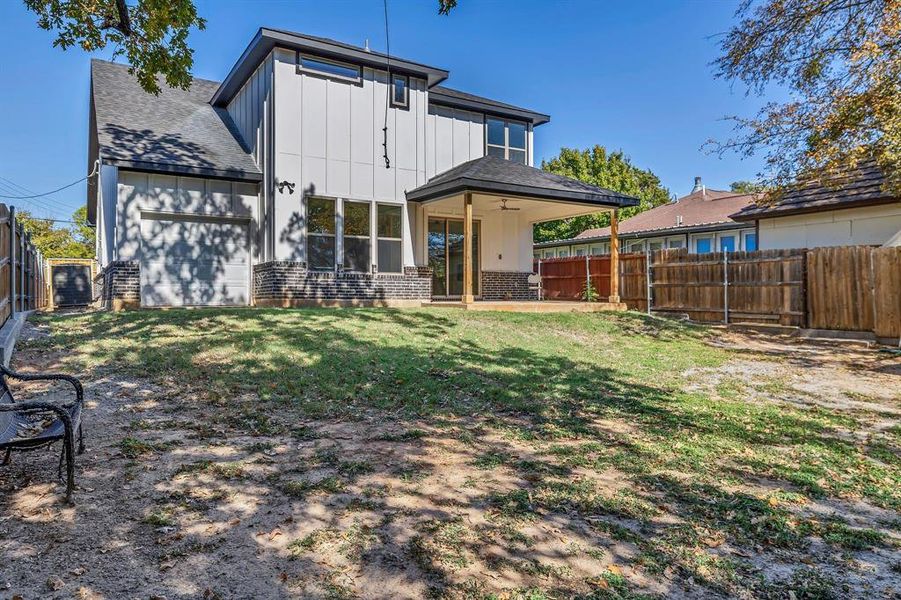 Rear view of property featuring brick siding, a fenced backyard, board and batten siding, and a patio area
