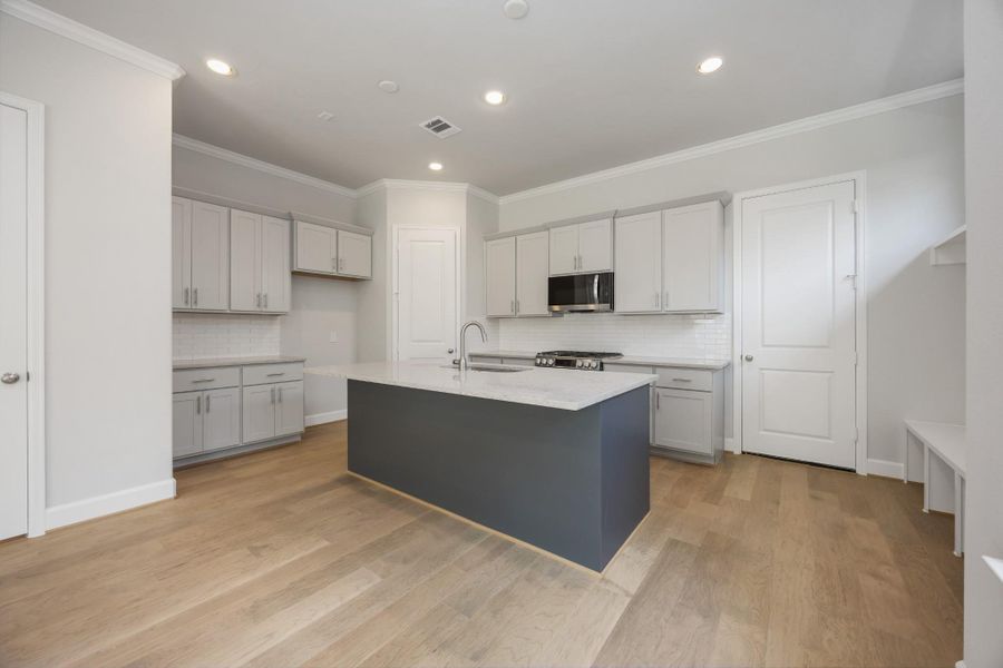 Designer's Touch: Two-toned cabinetry in cool grey and crisp white frames a generous quartz island, with subway tile backsplash and stainless appliances ready to inspire your inner chef. Designer's Touch: Two-toned cabinetry in cool grey and crisp white frames a generous quartz island, with subway tile backsplash and stainless appliances ready to inspire your inner chef.