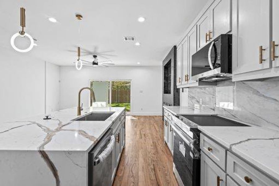 Kitchen featuring pendant lighting, stainless steel appliances, light stone counters, and sink