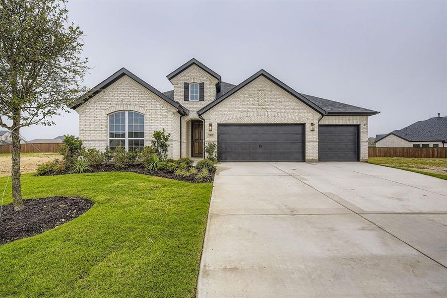 French country home featuring concrete driveway, brick siding, a garage, and a shingled roof