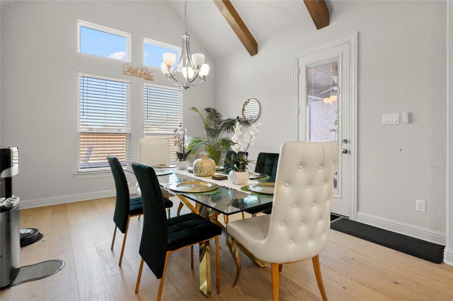 Dining area with light wood-type flooring, beam ceiling, a chandelier, and high vaulted ceiling Dining area with light wood-type flooring, beam ceiling, a chandelier, and high vaulted ceiling