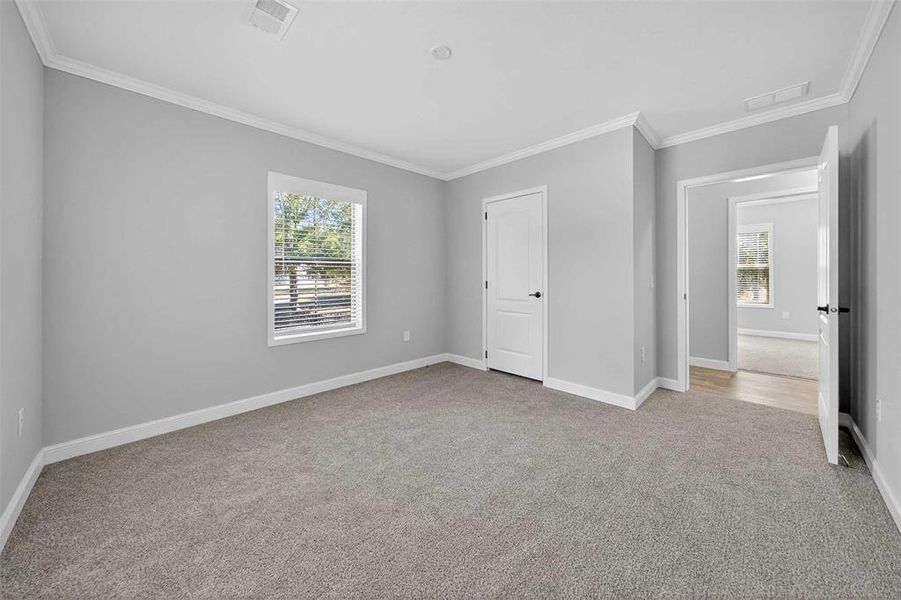 Unfurnished bedroom featuring ornamental molding and light carpet Unfurnished bedroom featuring ornamental molding and light carpet