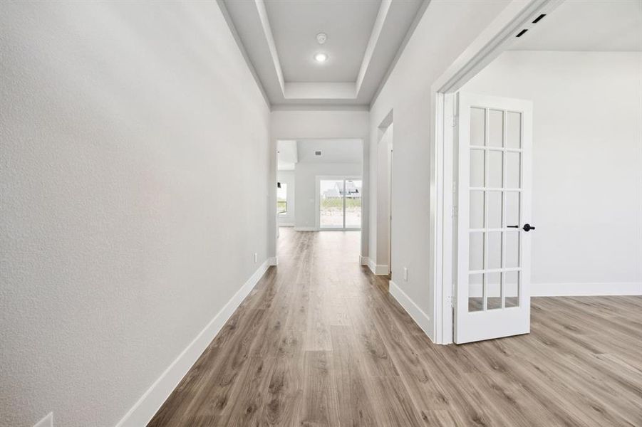 Corridor with light wood-style flooring and a raised ceiling