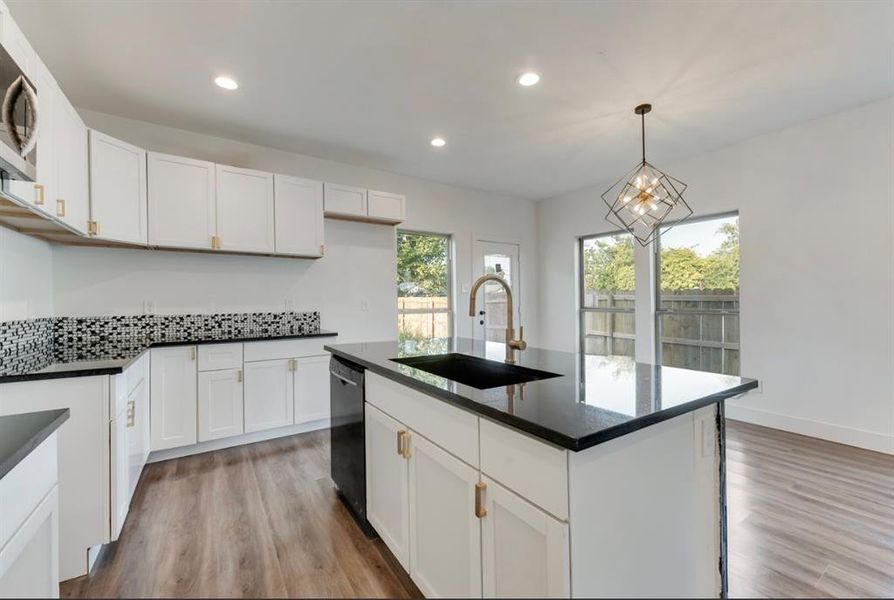 Kitchen with black dishwasher, sink, a wealth of natural light, and a center island with sink