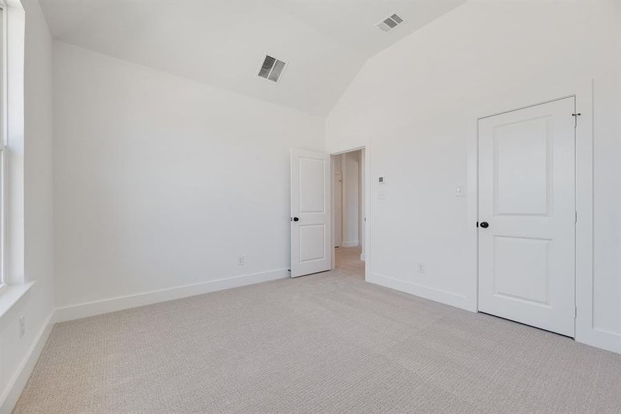 Unfurnished bedroom featuring light colored carpet and high vaulted ceiling Unfurnished bedroom featuring light colored carpet and high vaulted ceiling