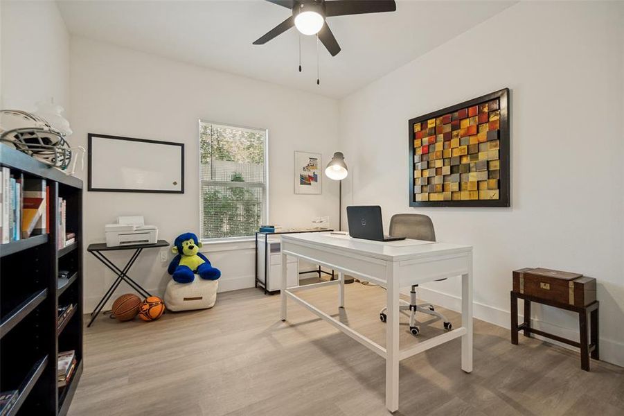 Bright interior room featuring light wood-finish flooring, a ceiling fan, and white walls Bright interior room featuring light wood-finish flooring, a ceiling fan, and white walls