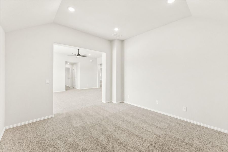 Empty bedroom with beige carpet, tray ceiling, and open doorway leading to living area with ceiling fan Empty bedroom with beige carpet, tray ceiling, and open doorway leading to living area with ceiling fan