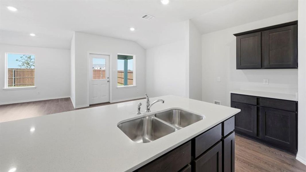 Kitchen featuring light wood-type flooring, recessed lighting, light stone countertops, and vaulted ceiling