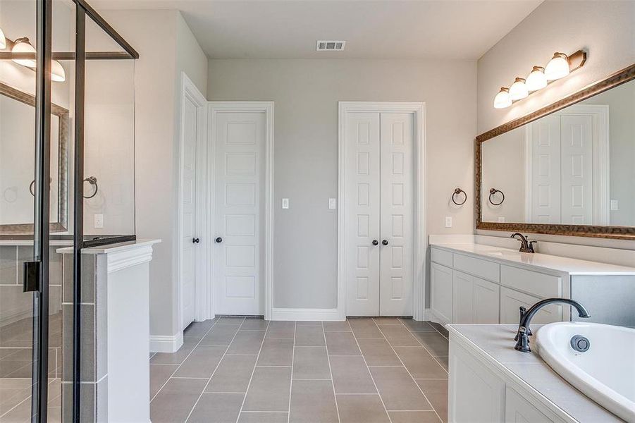 Bathroom featuring a bath, tile patterned flooring, and vanity