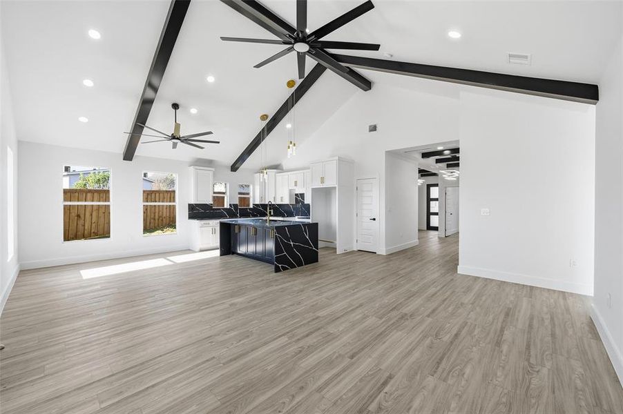 Unfurnished living room with beamed ceiling, light wood-style flooring, ceiling fan, high vaulted ceiling, and recessed lighting Unfurnished living room with beamed ceiling, light wood-style flooring, ceiling fan, high vaulted ceiling, and recessed lighting