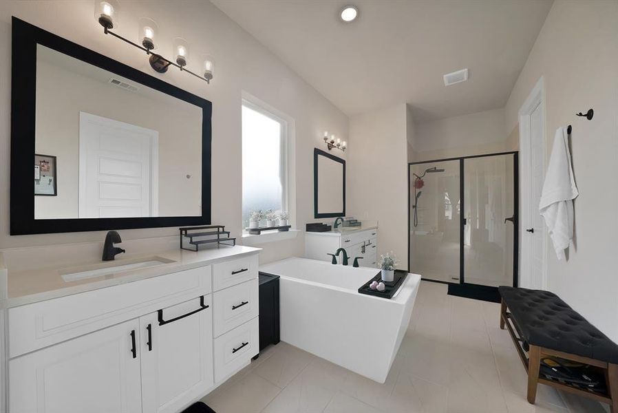 Spacious bathroom featuring a freestanding tub, dual vanities with white cabinetry, a glass-enclosed shower, and light-toned tile flooring Spacious bathroom featuring a freestanding tub, dual vanities with white cabinetry, a glass-enclosed shower, and light-toned tile flooring