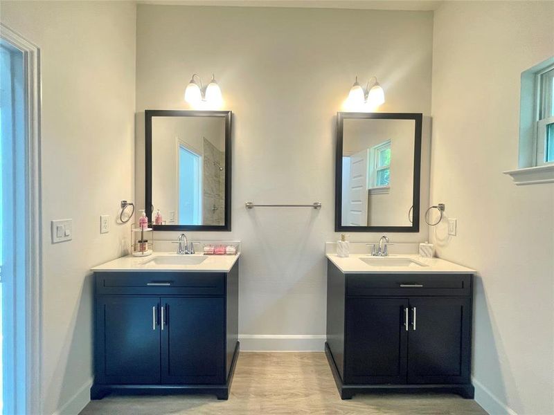 Bathroom featuring a sink, two vanities, wood finished floors, and baseboards
